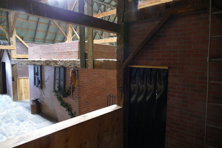 Interior of a rustic building with brick walls and wooden beams.