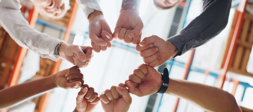Group of hands forming a circle with fists touching in the center.