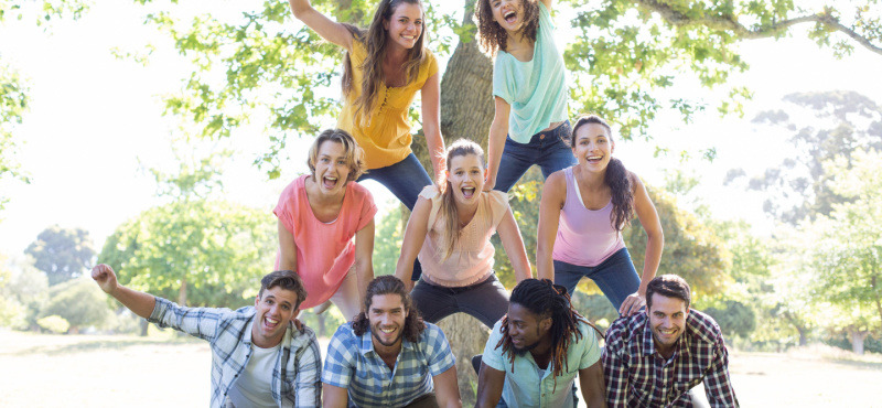 Group of people forming a human pyramid in a park.